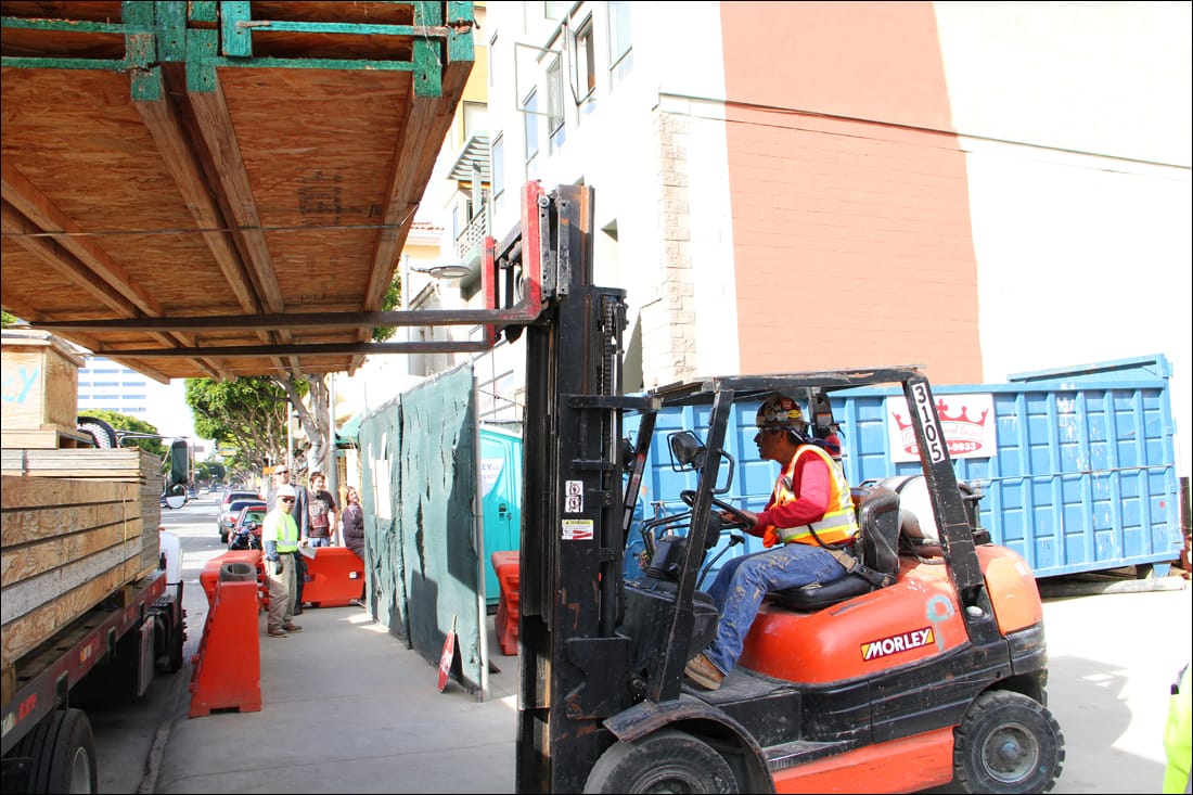 FROM HERE TO THERE: A forklift operator raises a load of lumber at the site of Parking Structure No. 6 on Monday. (Photo by Daniel Archuleta)