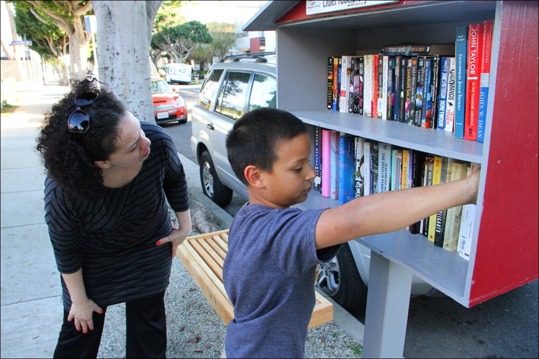 CHECKING IT OUT: Simon Johnson, 9, stocks books in his mother's Little Free Library on Monday as Santa Monica arts commissioner Tanya Merriman browses the selection. The library is part of an international effort to spread the written word. (Photo by Daniel Archuleta)