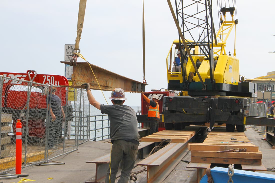 A work crew hoists a massive I-beam onto the deck of the Santa Monica Pier. The work is part of a the pier's Renewal Project. Much of the project will be focused on replacing most of the deck from the waterline to the western end of the historic landmark.