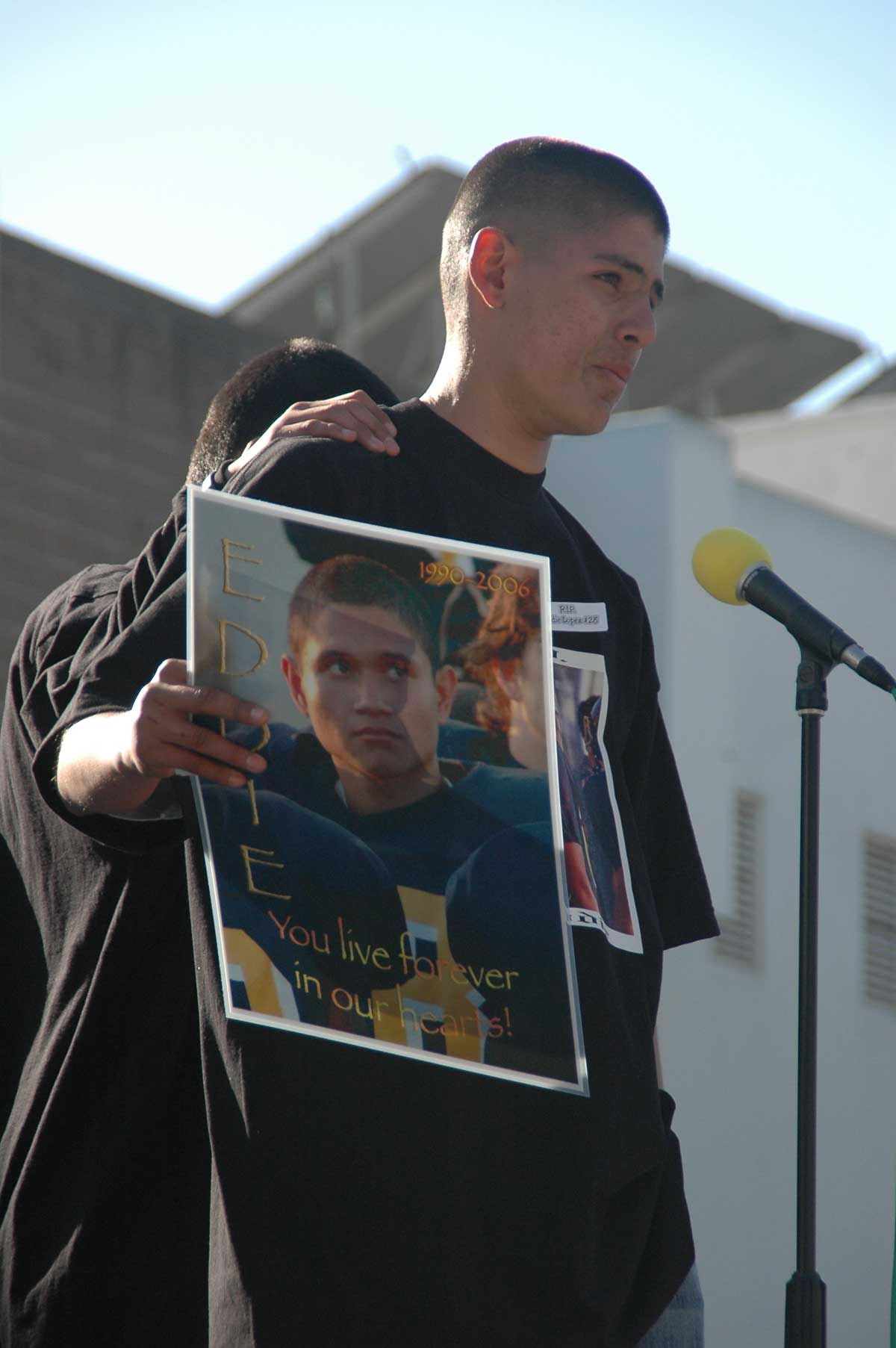 A friend of Eduardo 'Eddie' Lopez, 15, holds up a photo of the young man during a memorial service at Santa Monica High School in 2006. Lopez was shot and killed while walking with friends along Pico Boulevard. (File photo)