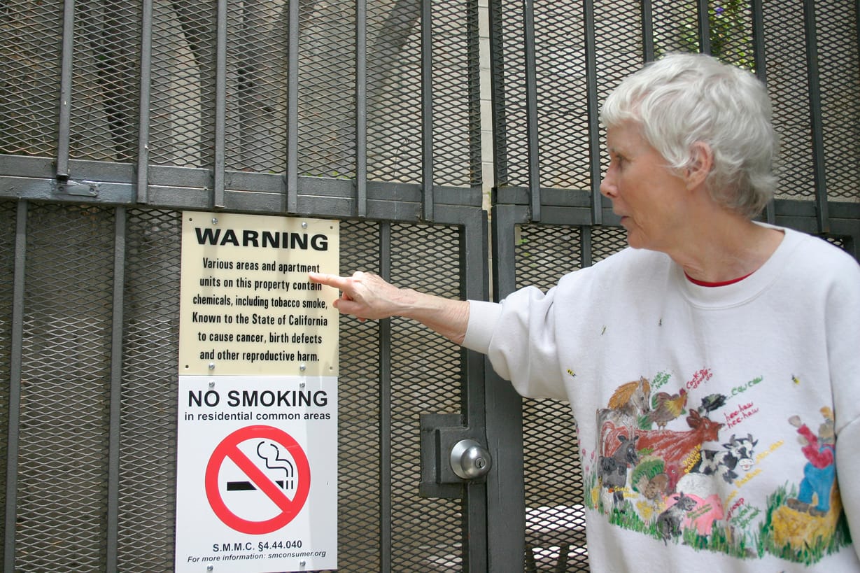 Bette Shapiro points out a 'no smoking' sign at her apartment complex on Fifth Street earlier this year before the City Council voted to ban smoking in apartments and condos for all those moving in after Nov. 22. (File photo)
