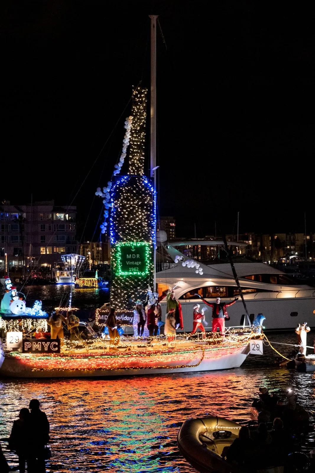 A boat covered with Christmas lights and a large wine bottle. 